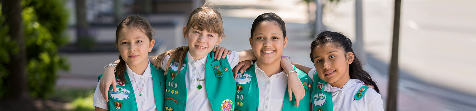  group of girl scouts walking outside smiling at camera 